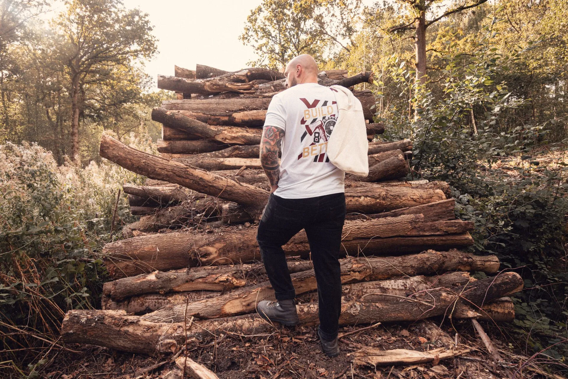 Back of the white 8x8 Build It Better T-shirt showing the large graphic beside stacked logs.