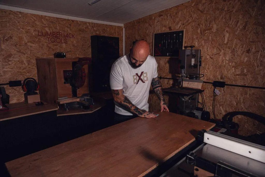 Man wearing the Raw 8x8 OG T-shirt while wiping a workshop bench.