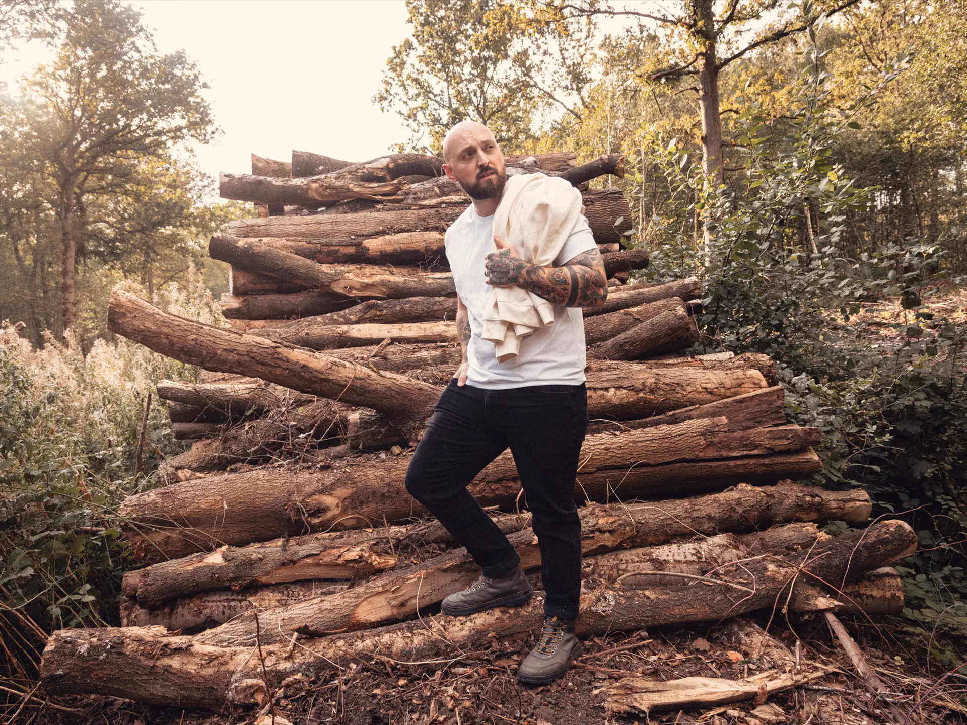 8×8 white tee by a stack of cut logs